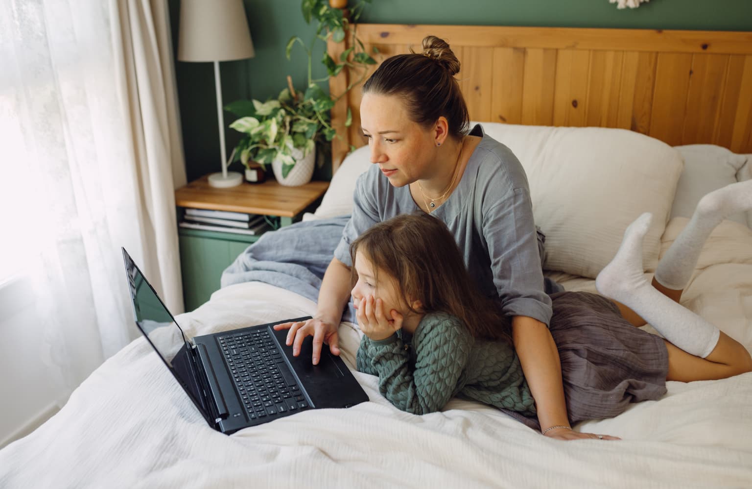 Mutter und Kind sitzen auf dem Bett und suchen nach der Rechnung im Deutsche Glasfaser Kundenportal