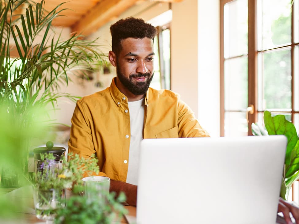 FAQ Deutsche Glasfaser - Mann im gelben Hemd arbeitet am Laptop