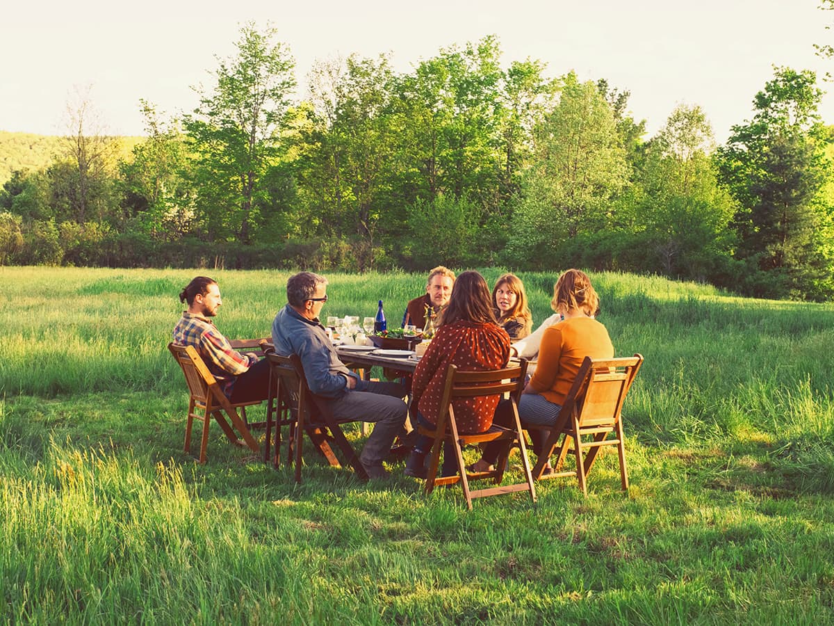 Eine Freundesgruppe sitzt im Grünen und haben ein Picknik