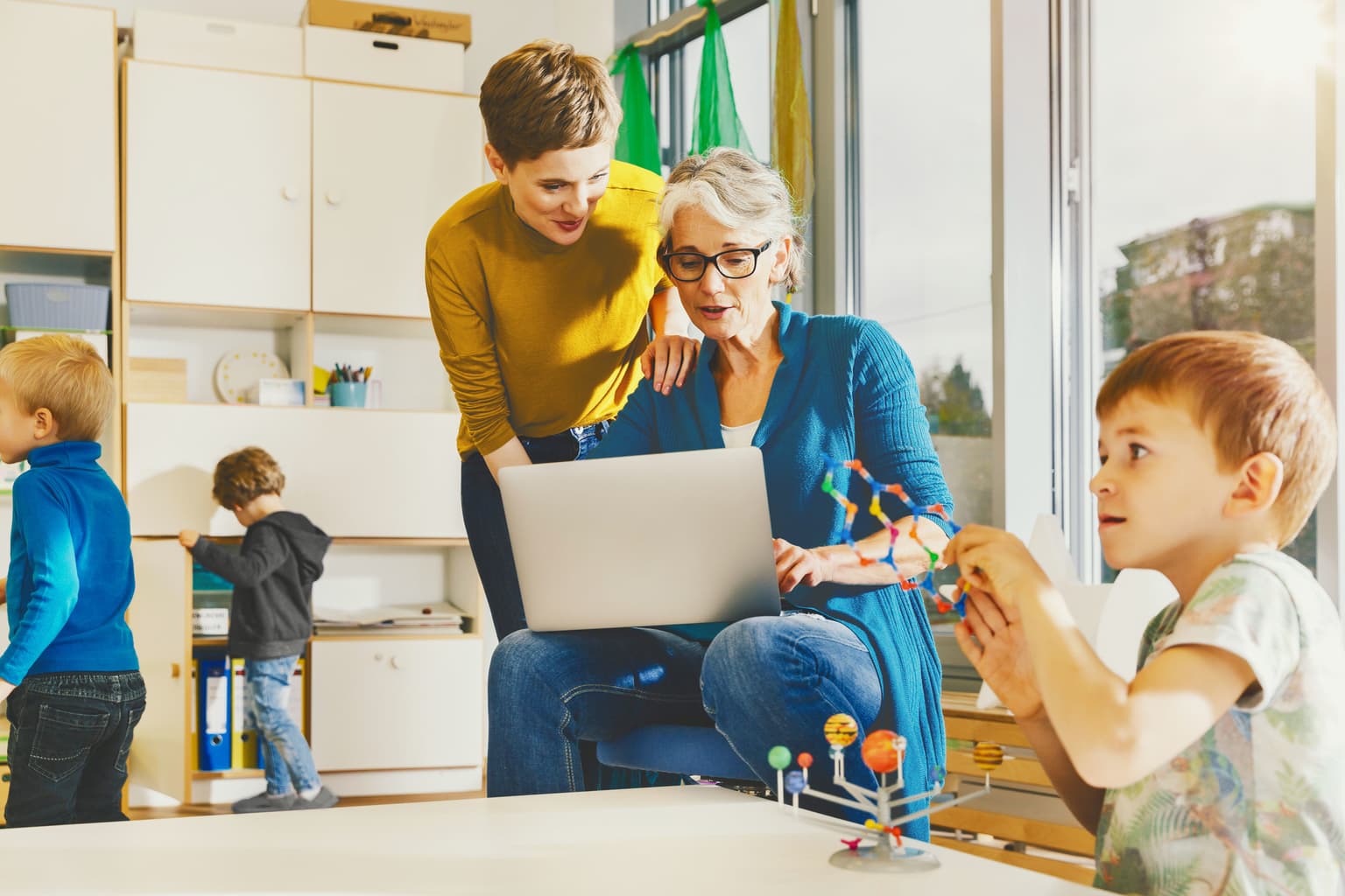 Public Deutsche Glasfaser Frauen helfen sich am Laptop, während Kinder I