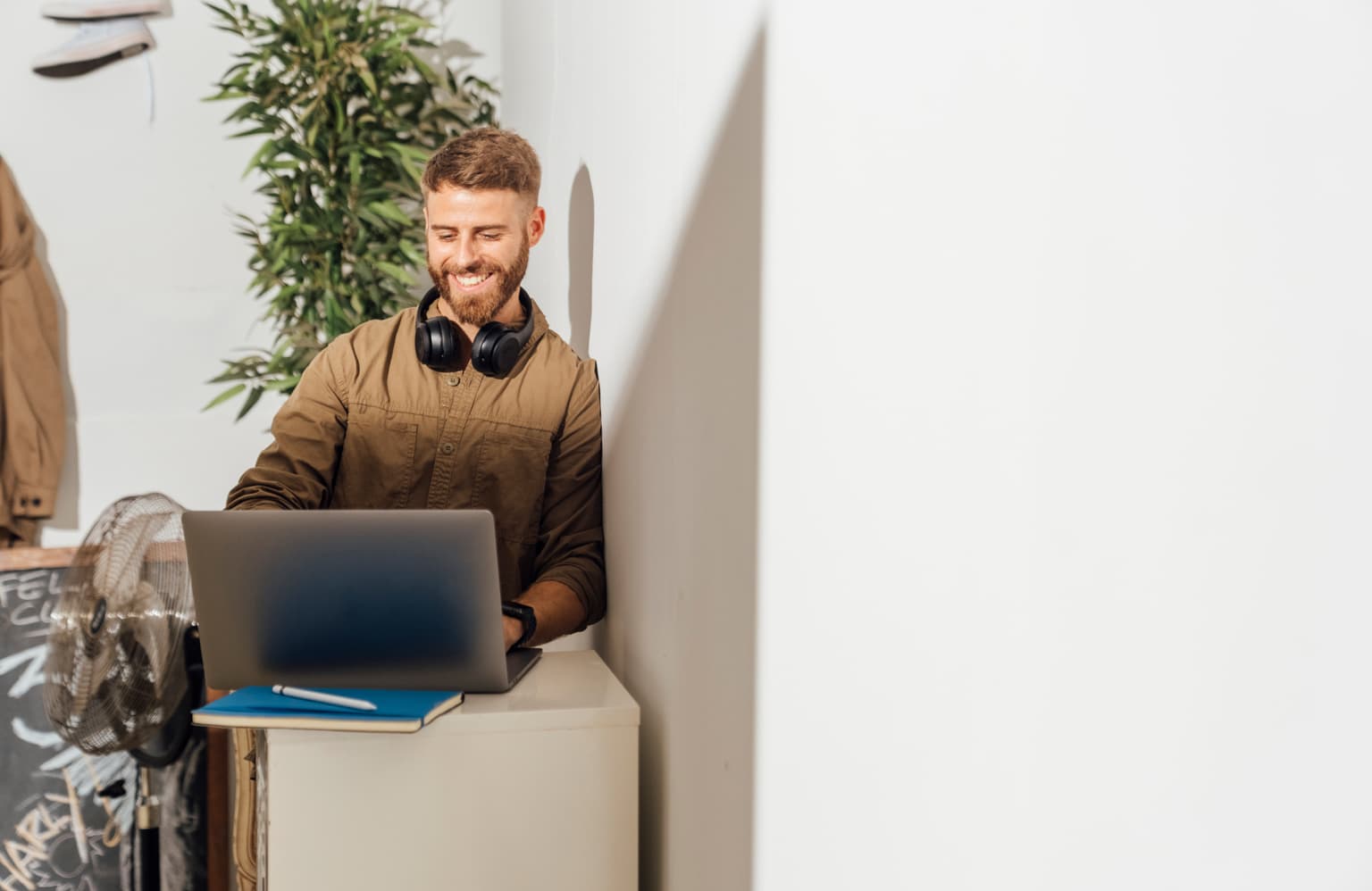 Mann sitzt mit Kopfhörern am Laptop und surft im Internet