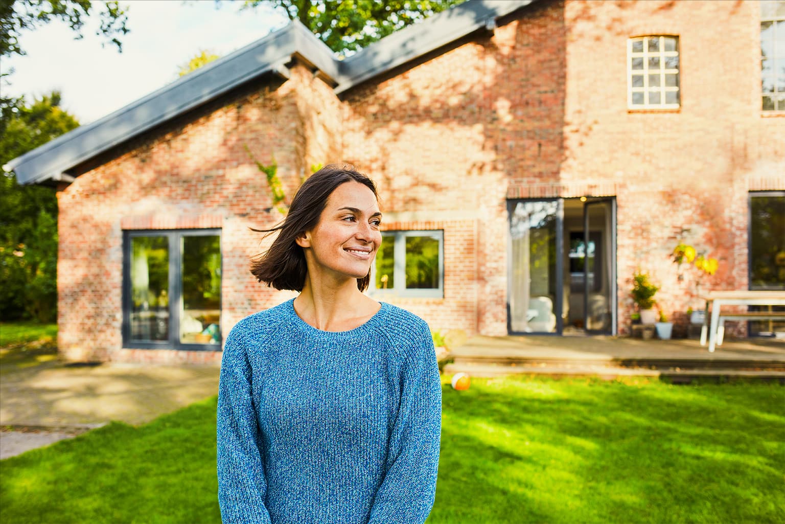 Frau steht lachend vor ihrem Haus