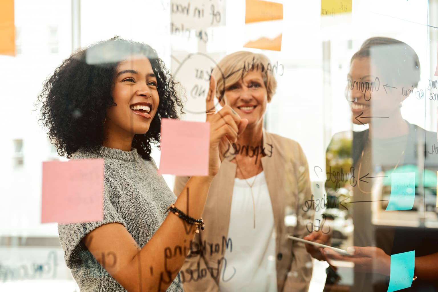 Implementieren und Integrieren von Projekten, Team arbeitet im Brainstorming mit Zetteln an einer Glaswand