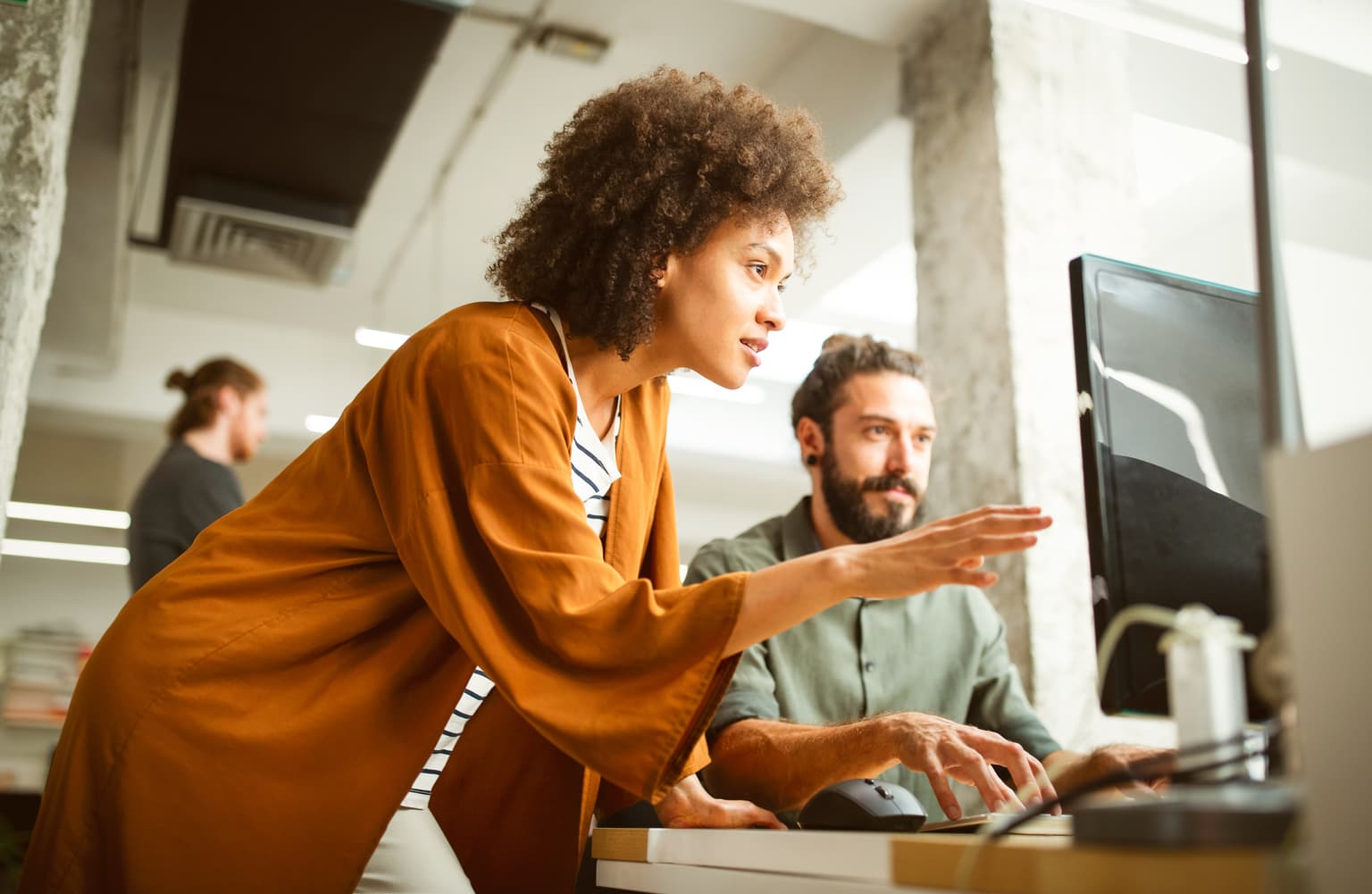 B2B Technologien vorbereiten auswählen, Frau erklärt ihrem Arbeitskollegen ein Projekt am PC