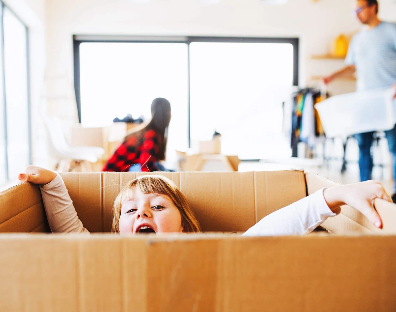 Kind sitzt in einer Umzugskiste und spielt