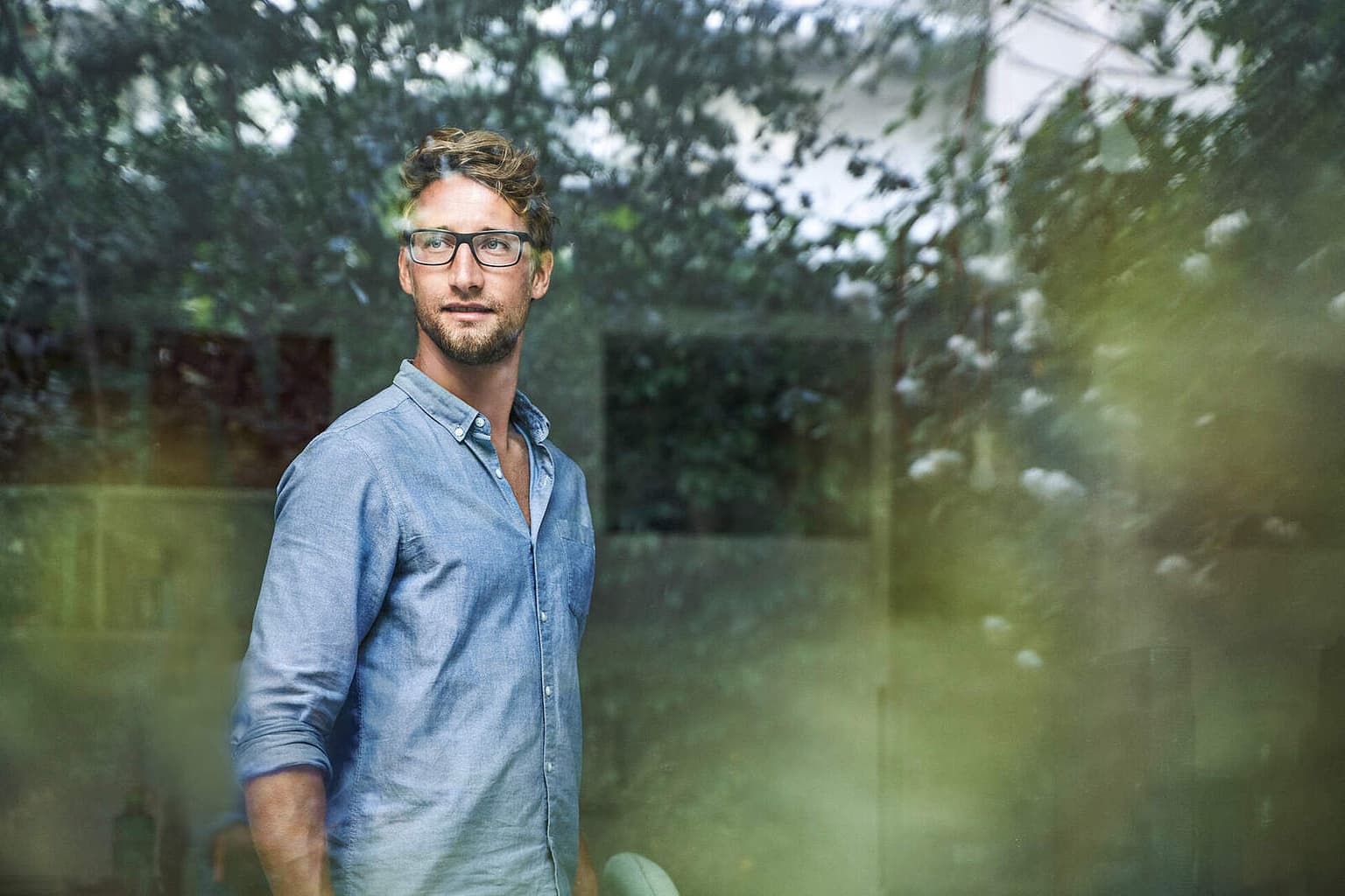 Mann mit Brille schaut aus dem Fenster