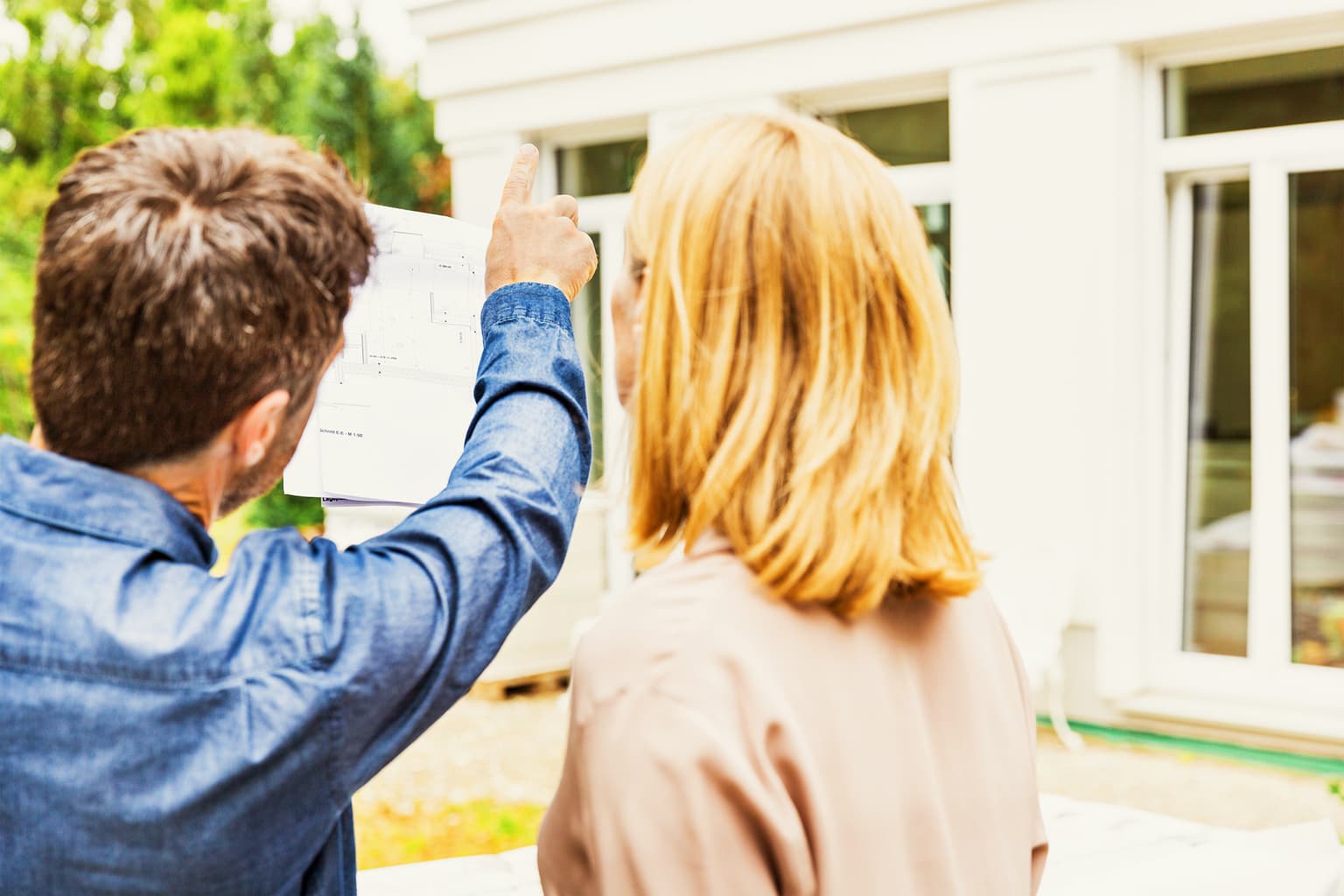 Bauphase Grundstück - Paar schaut sich Bauskizzen auf ihrem Gruntsück an