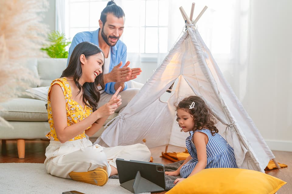 Eine Familie sitzt mit ihrer Tochter zusammen und spielen mit ihr