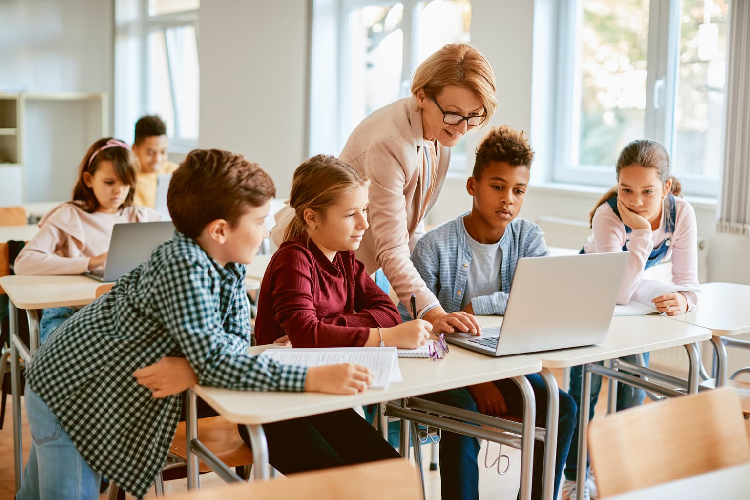 B2B DG Public - Lehrerin erklärt ihren Schulkindern am Pc die Aufgabe