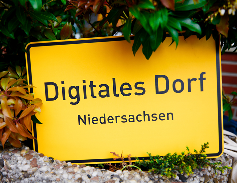 Gelbes Ortsschild mit Aufschrift „Digitales Dorf Niedersachsen“.